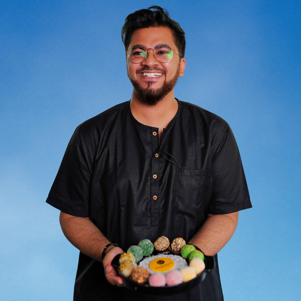 Chef Kétan holding a plate of assorted Laddoos against a blue background